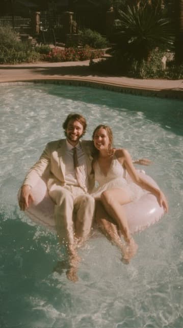 Bride and groom laughing on an inflatable ring in a pool