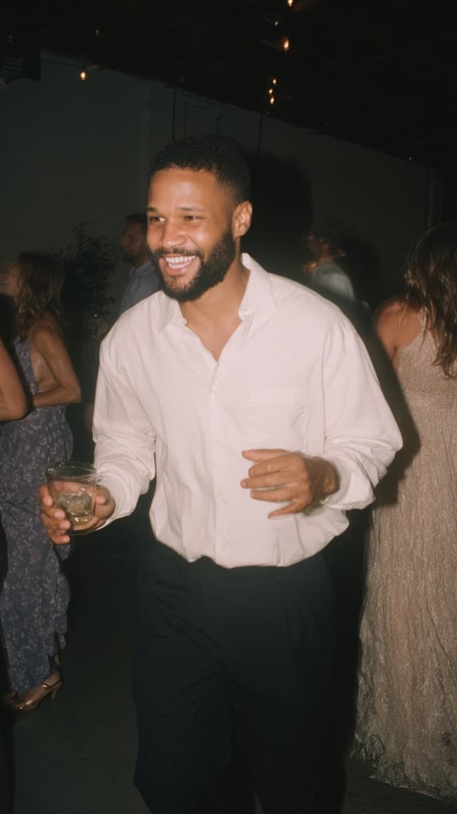 Smiling guest dancing with a drink at a party